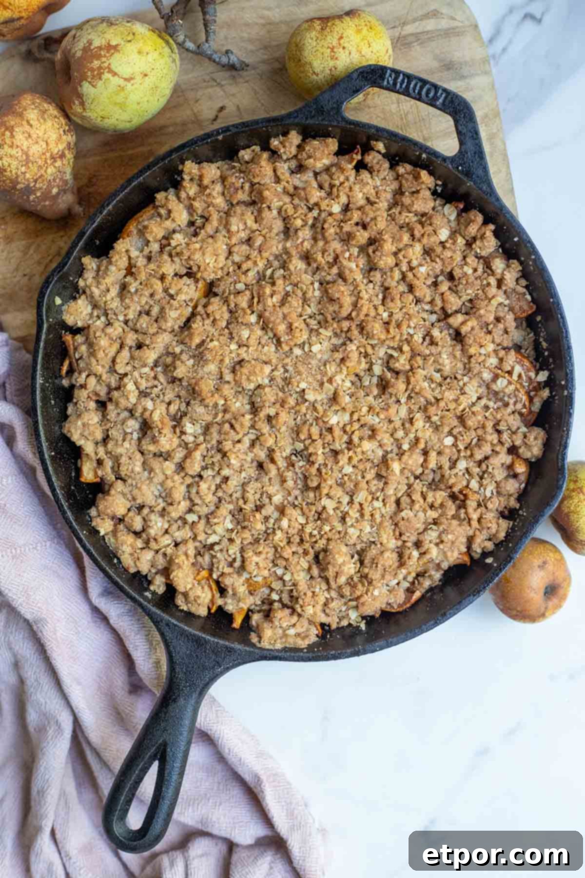 Pear crisp right out of the oven in a cast iron skillet. Pears surround the skillet.