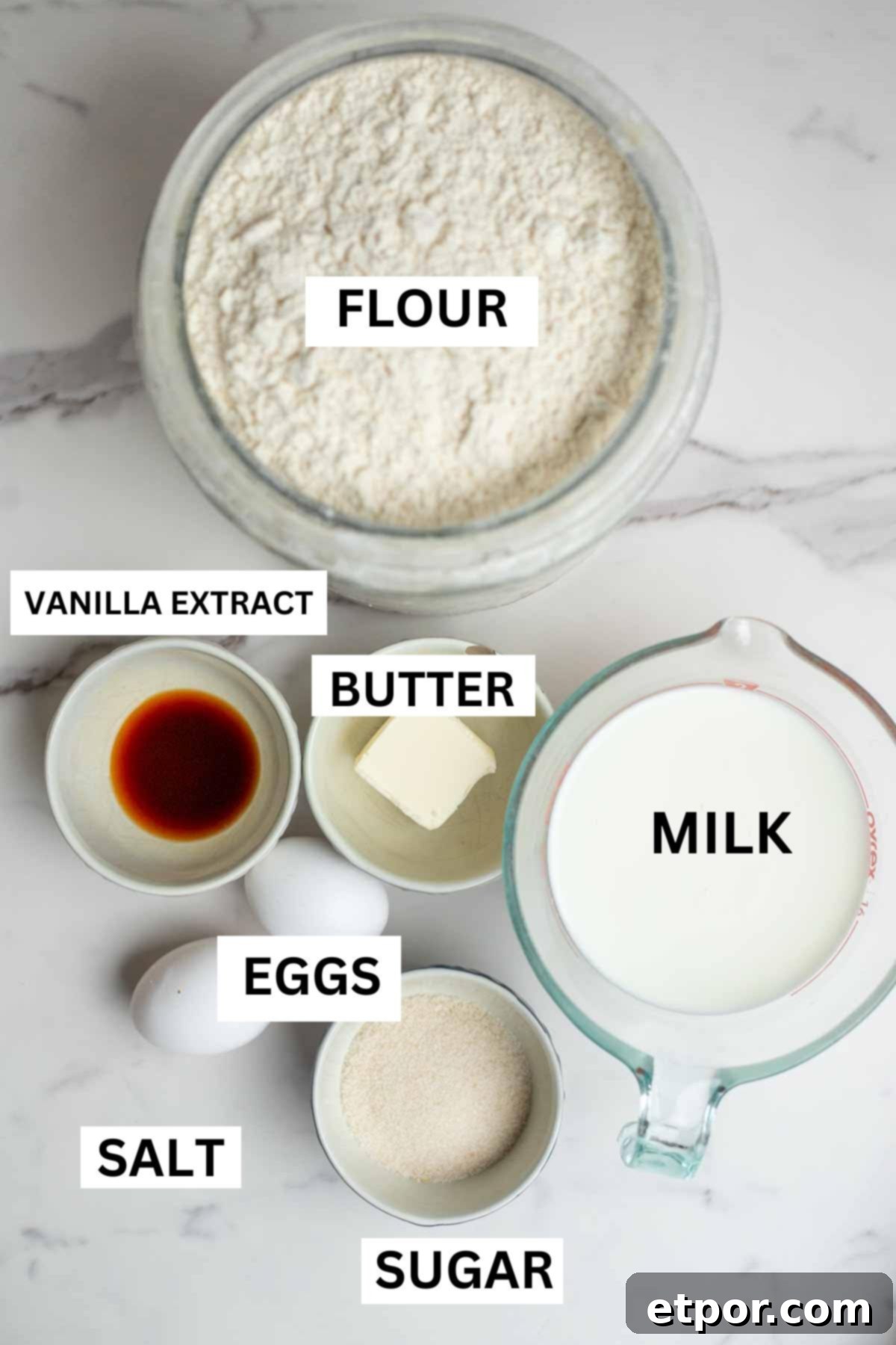 Bowls of flour, butter, sugar, vanilla extract, milk, eggs and salt are also on the countertop.