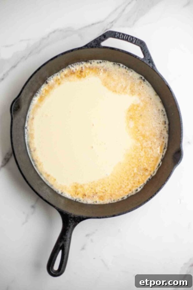Pancake batter in a cast iron skillet.