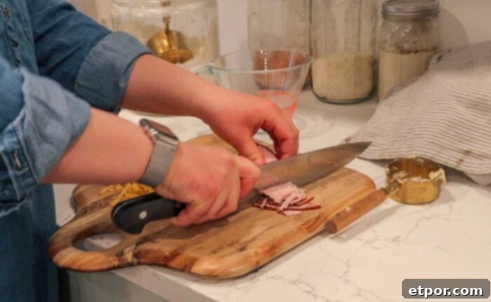 Dicing ham on a cutting board for breakfast biscuits.
