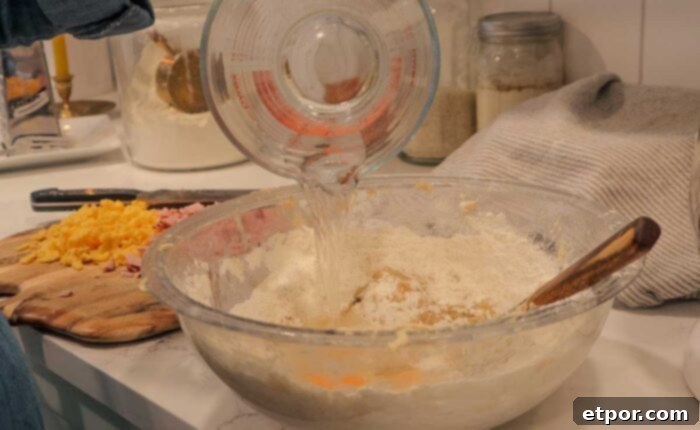 Pouring wet ingredients into dry ingredients for breakfast biscuit dough.
