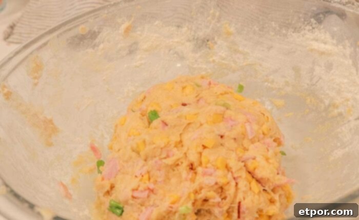 Mixing breakfast biscuit dough in a glass bowl.