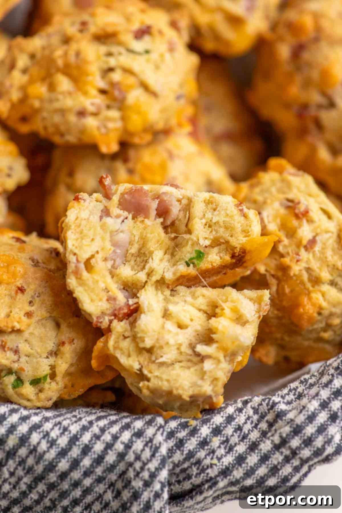 Inside a ham and cheese biscuit with a basket full of biscuits. The biscuit is cut in half showing the fluffy interior.